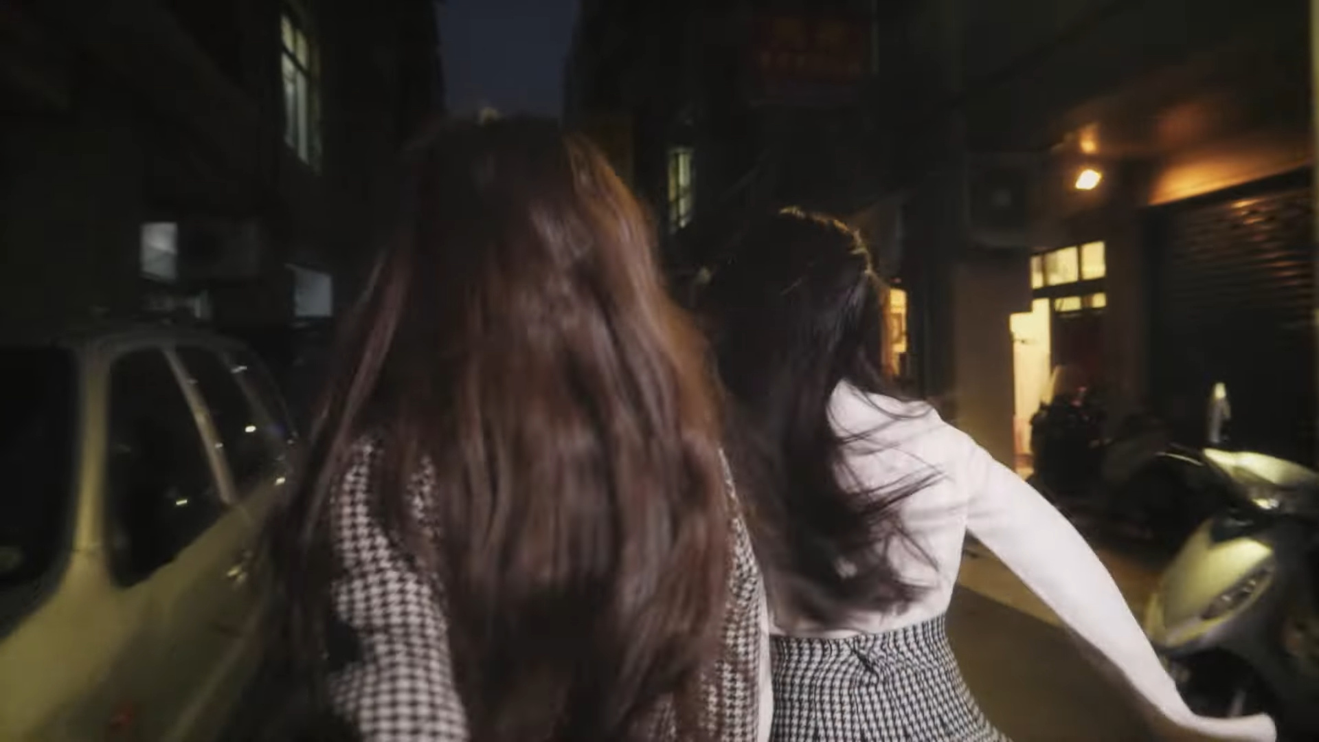 Heejin and Hyunjin holding hands and running through the city.